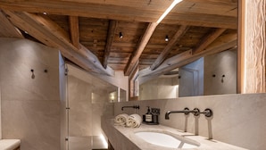 Ein modernes Badezimmer mit einem großen Waschbecken, Holzbalken und einer Duschkabine aus Glas.