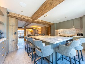 A modern kitchen with a large island, bar stools, and wooden beams. - Luxurious 6-room apartment with hammam, fireplace and parking in Val-d'Isère (Val-d'Isère)