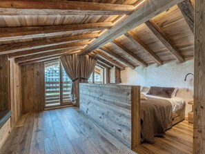 A rustic wooden room with a sloped ceiling, a bed with a headboard, and a window with curtains. - Luxurious 6-room apartment with hammam, fireplace and parking in Val-d'Isère (Val-d'Isère)