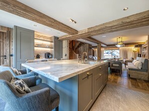 Una cocina amplia con una isla grande, vigas de madera y electrodomésticos modernos.