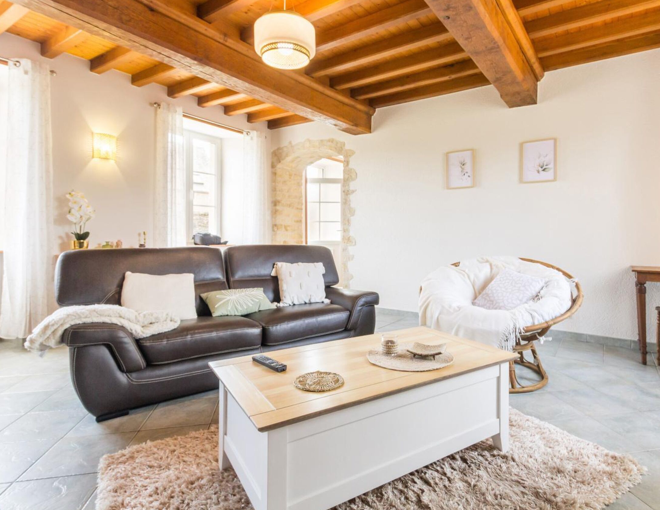 A cozy living room with a leather sofa, a wooden coffee table, and a wicker chair.