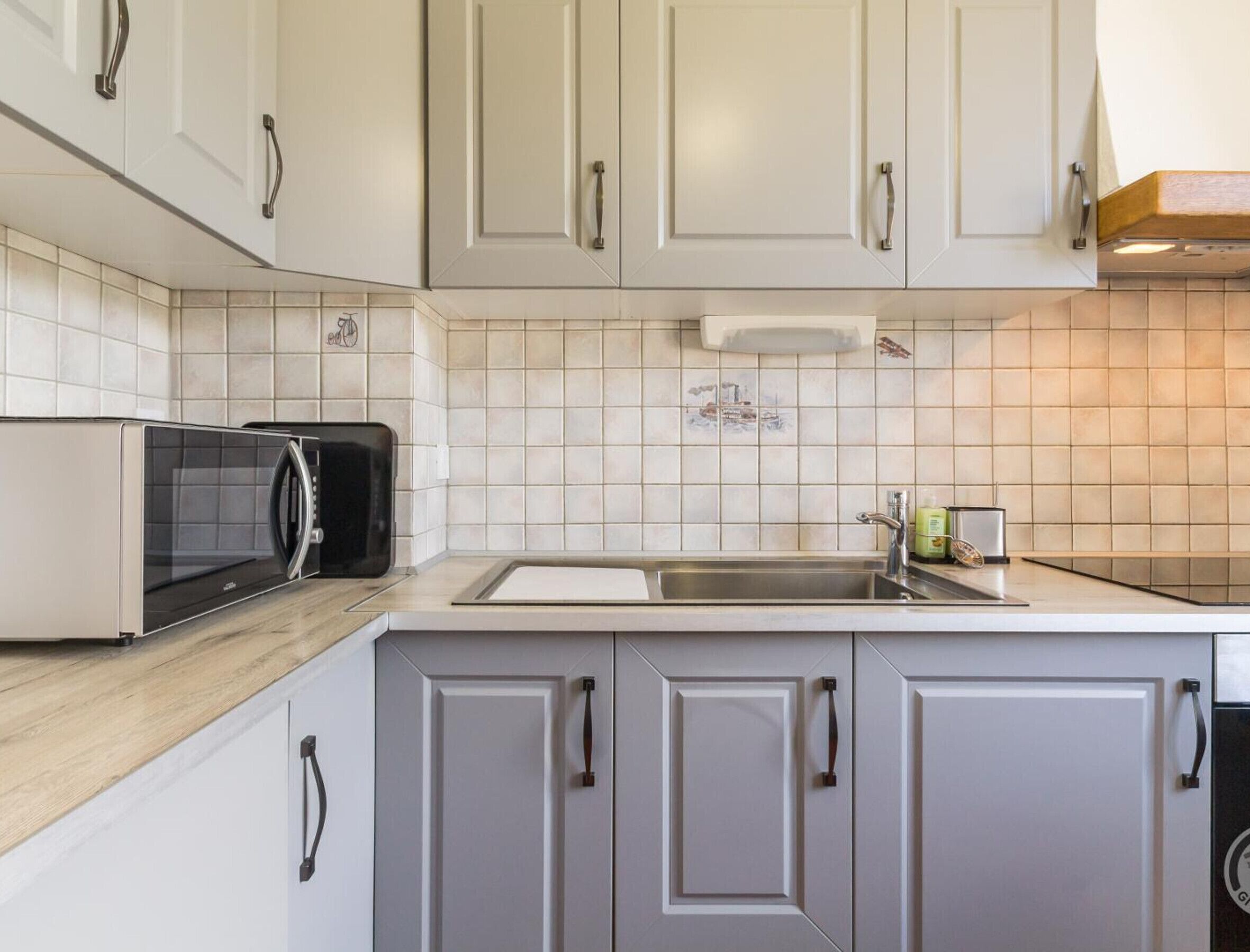 Una cocina moderna con armarios blancos, un microondas y un lavamanos.