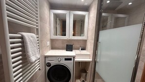 A compact bathroom with a washing machine, a sink, and a mirror. - 9-person apartment with parking in Tignes Val Claret (Tignes)