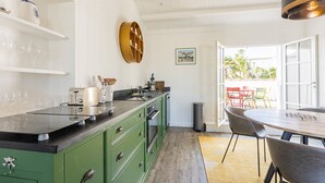 A modern kitchen with green cabinets, a black countertop, and a dining area with a round table and chairs. - Modern apartment with large terrace in Ars-en-Ré (Ars-en-Ré)