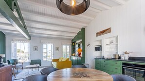 A spacious kitchen with a round wooden table surrounded by chairs, a green cabinet, and a window with a view. - Modern apartment with large terrace in Ars-en-Ré (Ars-en-Ré)