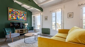 A living room with a green wall, a yellow sofa, a checkered chair, a round coffee table, and a colorful painting. - Modern apartment with large terrace in Ars-en-Ré (Ars-en-Ré)