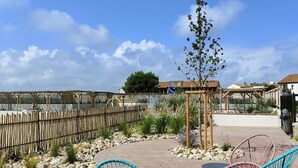 An outdoor patio area with wicker chairs, a small tree, and a wooden pergola. - Cozy T2 with terrace in Le Barcarès (Le Barcarès)