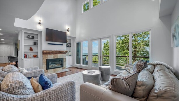 A spacious living room with a fireplace, comfortable seating, and large windows offering a view of the outdoors. - Black Bear Ridge | Games, Hot Tub, Deck w/ Views (Mentone)