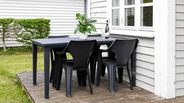 A patio with a table and chairs, a potted plant, and a bottle of wine. - 6 Person Holiday Park Home in Asperup (Middelfart)