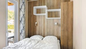 Un dormitorio con cama, paneles de madera y una estantería blanca.