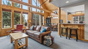 Un intérieur de cabine spacieux, comprenant une grande table à manger en bois, un canapé en cuir et un coin cuisine avec un comptoir-bar.