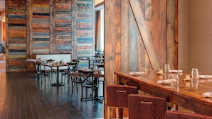 A restaurant interior with wooden walls, dark flooring, and a mix of dining tables and chairs. - Across Raleigh Convention Center + Dining & Pool (Raleigh)