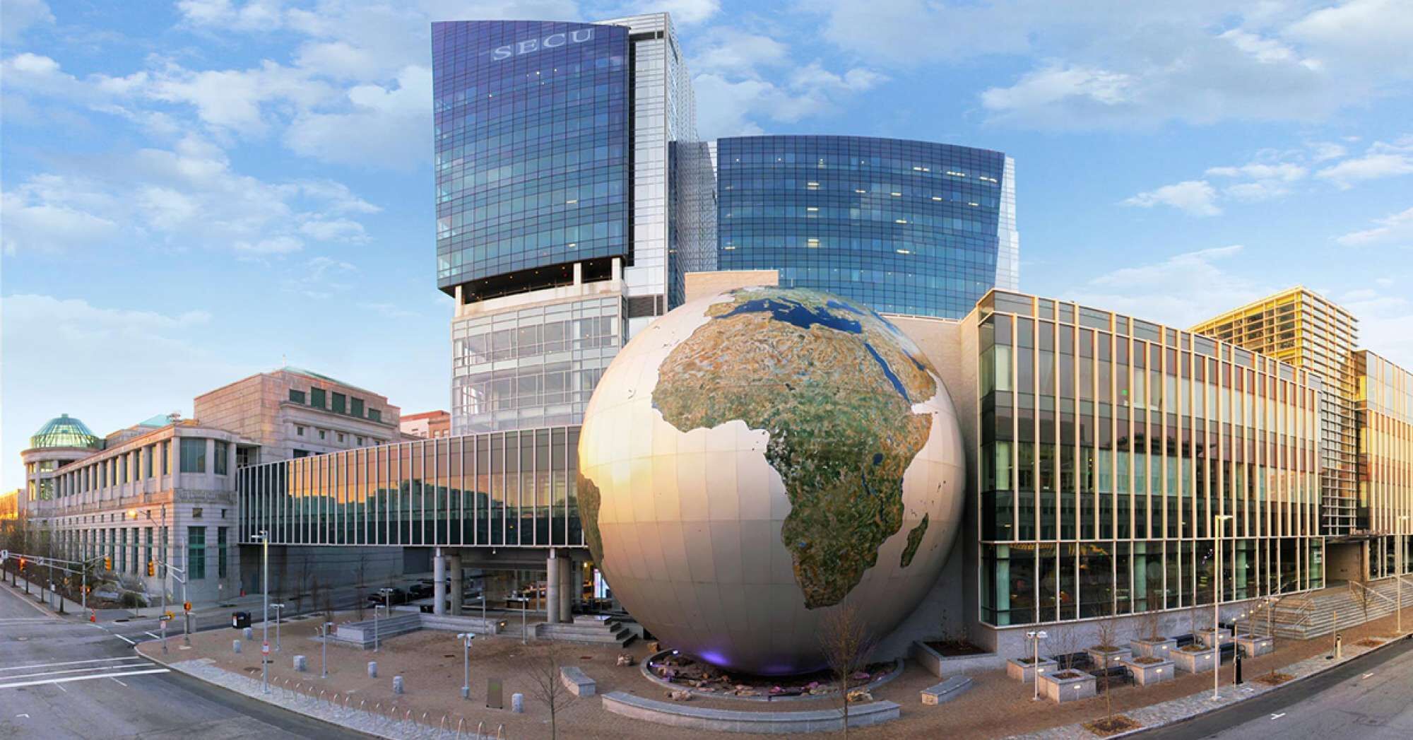 Un edificio moderno con una gran escultura de un globo terráqueo en primer plano.