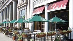 Outdoor seating with green umbrellas and potted plants at a coffee shop. - Georgetown Views | Fitness Center. Great Events (Arlington)