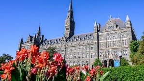 A historic building with multiple towers and arched windows, surrounded by lush greenery. - Georgetown Views | Fitness Center. Great Events (Arlington)