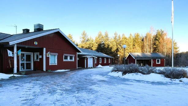 En röd byggnad med en överbyggd entré och en mindre, intilliggande byggnad.
