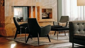 A modern living room with a marble wall, a fireplace, and a seating area with a sofa and chairs.
