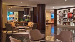 A modern lobby with a seating area, large pillars, and a bookshelf with various items.