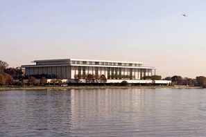 A modern building with a flat roof, rectangular windows, and a flat facade, situated by a calm body of water.