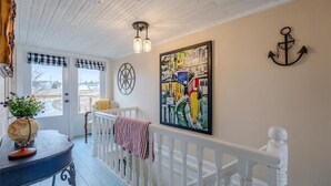 Une chambre décorée sur le thème de la côte, avec une balustrade blanche, un globe posé sur une table et un tableau coloré accroché au mur.