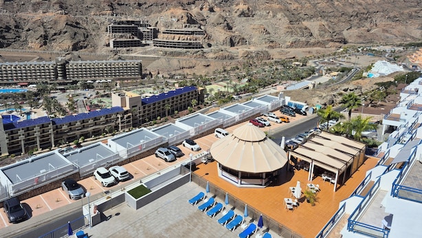 A hotel with multiple buildings, a parking area, and a pool.