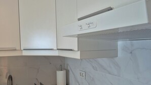A modern kitchen with white cabinets, a stainless steel sink, and a marble backsplash.