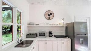 Een moderne keuken met witte kasten, een roestvrijstalen koelkast, een koffiezetapparaat en een klok aan de muur.