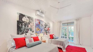 Een hotelkamer met twee bedden, een rood tapijt en grote abstracte schilderijen aan de muur.