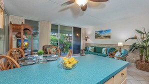 Una cocina con encimera azul, sillas de madera, una mesa de comedor y un ventilador de techo.