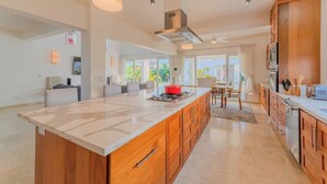 A spacious kitchen with a large island, wooden cabinets, and a view to the outdoors.