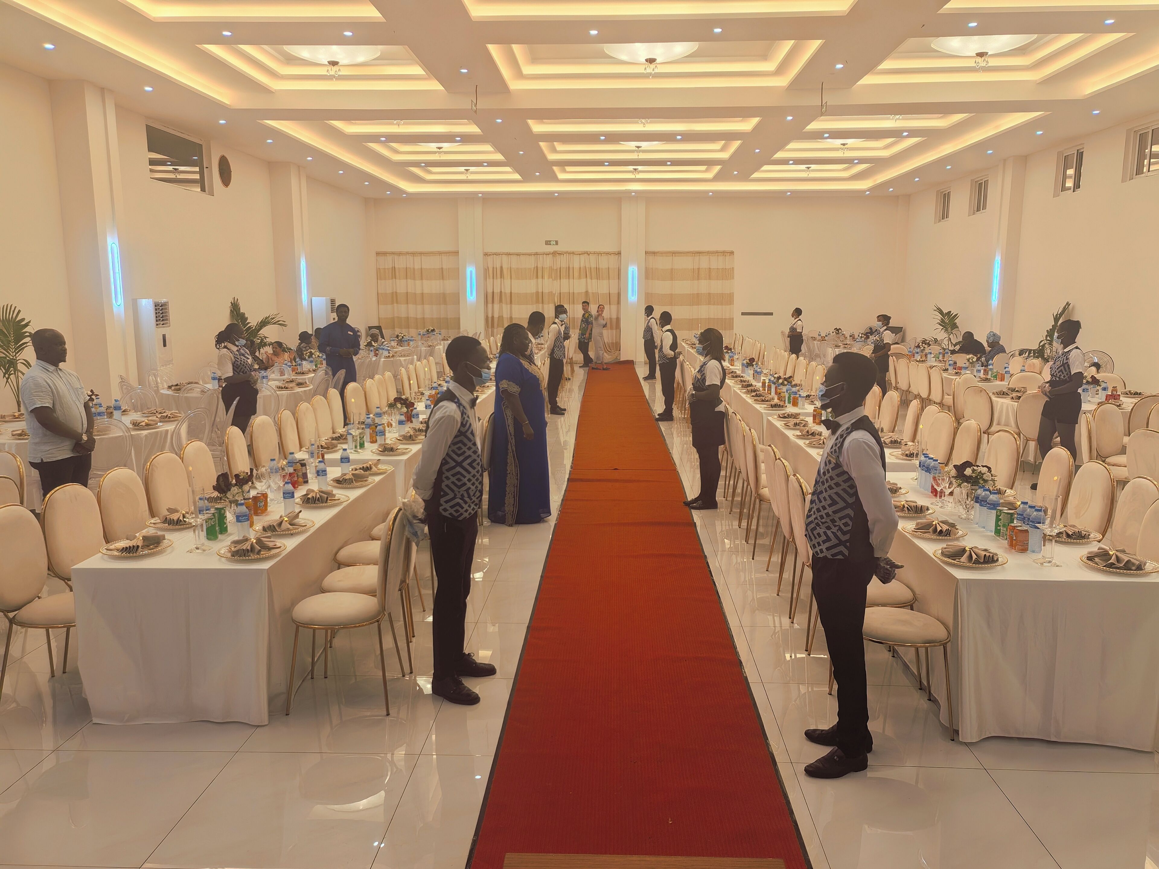 Un salón de banquetes con largas mesas, sillas y personal.