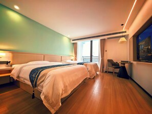 A hotel room with a large bed, bedside tables, a desk, and a TV. - bintumani hotel (Freetown)