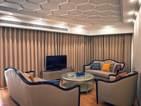A modern living room with a television, sofas, a coffee table, and a patterned ceiling.