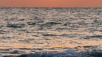 A sunset over the ocean with waves crashing onto the shore.
