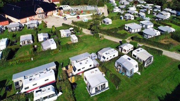 Ein Caravanpark mit mehreren Wohnwagen und einem Gebäude mit rotem Dach.
