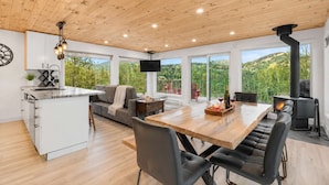 A modern kitchen with a central island, a dining area with a wooden table, and a cozy seating area with a sofa and chairs.