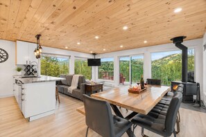 A modern kitchen with a central island, a dining area with a wooden table, and a cozy seating area with a sofa and chairs.