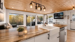 A modern kitchen with a wooden ceiling, a large window, and a built-in dishwasher.