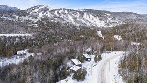 A snow-covered landscape with a road, buildings, and mountains. - Spa & Sauna | Le Hors-Piste (Saint-Côme)