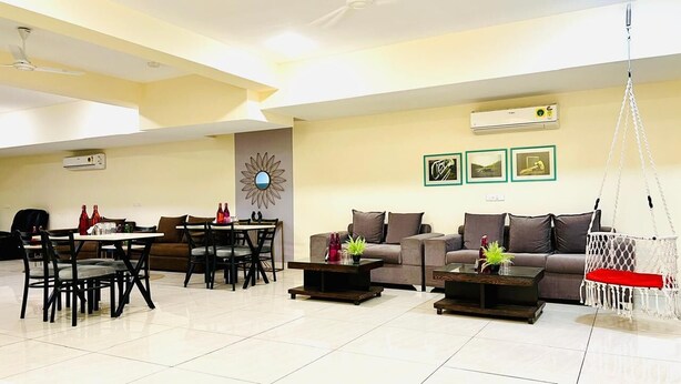 A spacious living area with a dining table, sofas, and a hanging chair.