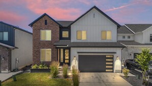 A two-story house with a garage, a brick facade, and a well-maintained lawn.