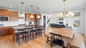 A modern kitchen with wooden cabinets, a central island with bar stools, and pendant lighting.