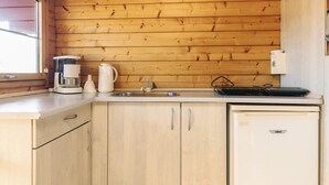 A compact kitchen with wooden panel walls, a sink, a coffee maker, and a small refrigerator. - 4 Person Holiday Park Home in Gorlev (Gørlev)
