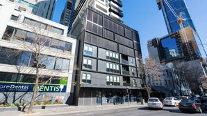 A modern building with multiple floors, large windows, and a sign for a dental office.