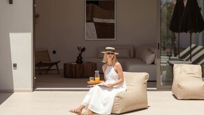 Un área de estar moderna al aire libre con piscina, una puerta de vidrio que da a un espacio de estar y un árbol de fondo.