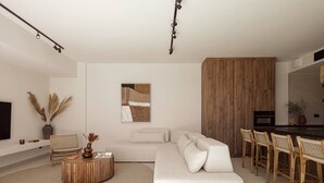 Una sala de estar moderna con un sofá blanco, una mesa de centro de madera y un comedor con sillas de mimbre.