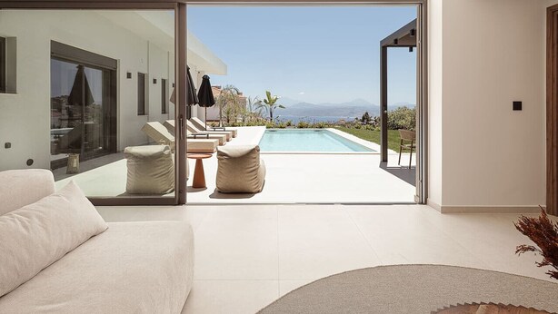 Una sala de estar moderna con un amplio ventanal que da a una zona de piscina.