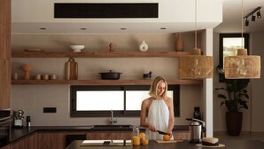 Una cocina moderna con una isla central, estanterías de madera y luces colgantes.