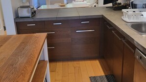 Eine moderne Küche mit Holzschränken, einem integrierten Geschirrspüler und einer großen Kücheninsel mit Spüle.