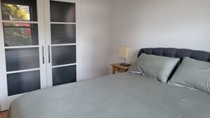 Ein Schlafzimmer mit Bett, Nachttisch, Lampe und Kleiderschrank mit Milchglasschranktüren.
